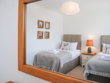 A reflection of a bedroom with two single beds and a nightstand with a lamp at 5 Ocean Reach in Bolberry