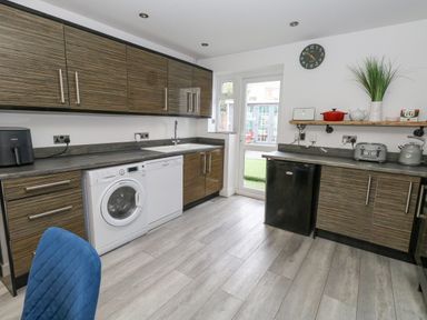 A kitchen with wooden cabinets washing machine dishwasher and small fridge at Beachaven in Weymouth