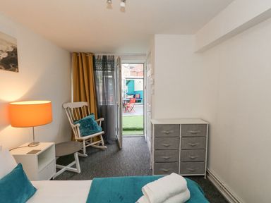 A bedroom with a bed towels rocking chair side table lamp and storage drawers at Beachaven in Weymouth
