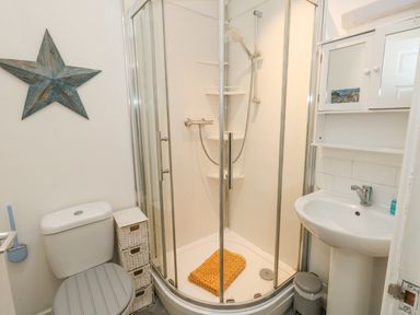 A bathroom with a shower enclosure toilet sink small cabinet and a star wall decoration at Beachaven in Weymouth