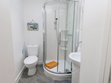 A bathroom with a toilet a corner shower and a sink at Beachaven in Weymouth