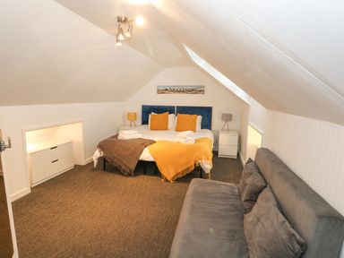 A bedroom with a double bed two bedside tables a sofa and framed picture at Beachaven in Weymouth