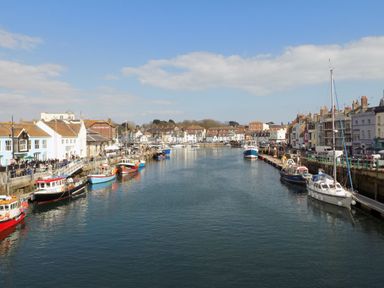 A harbor with boats docked along both sides and buildings lining the waterfront at Beachaven in Weymouth