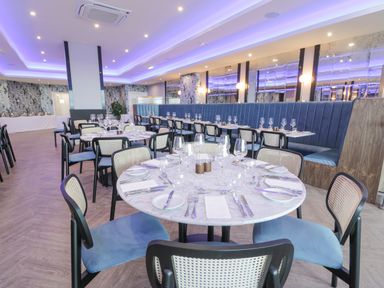 A dining area with round and rectangular tables set with plates glasses and cutlery at Classic Lodge 25 in Dyserth