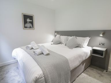 A bedroom with a double bed with rolled towels and pillows and a small wall shelf at Classic Lodge 25 in Dyserth