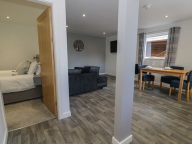 A living room with a sofa and wall decor a dining area with a table and chairs and a bedroom with a bed at Classic Lodge 25 in Dyserth