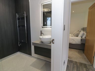 A bathroom with a sink and mirror next to a bedroom with a made bed at Classic Lodge 25 in Dyserth