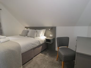 A bedroom with a double bed pillows bedside table chair and dresser at Premier Lodge 41 in Dyserth