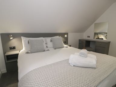 A bedroom with a bed with pillows and folded towels on a blanket at Premier Lodge 41 in Dyserth
