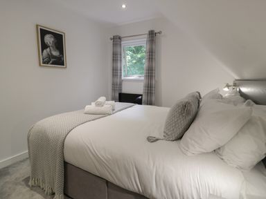 A bedroom with a bed towels on the bed and a window with plaid curtains at Premier Lodge 41 in Dyserth
