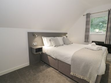A bedroom with a double bed gray headboard and bedside shelves at Premier Lodge 41 in Dyserth