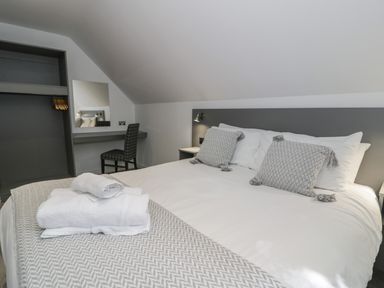 A bedroom with a bed with pillows and folded towels a chair a mirror and an open closet at Premier Lodge 41 in Dyserth
