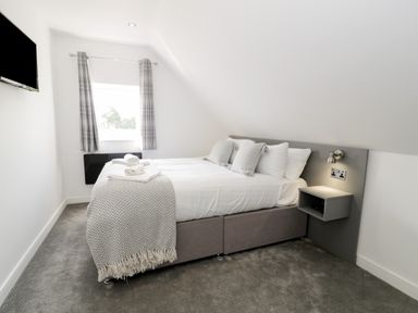A bedroom with a bed pillows bedside shelf and window with curtains at Classic Lodge 15 in Dyserth