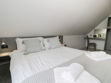 A bedroom with a double bed pillows and towels next to a chair and a desk with a mirror at Classic Lodge 15 in Dyserth
