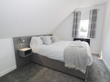 A bedroom with a double bed nightstand reading lights window with curtains and carpet at Classic Lodge 15 Dyserth