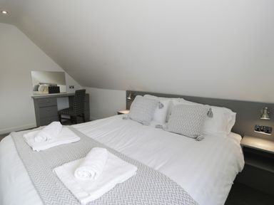 A bedroom with a double bed with folded towels a desk with a chair and a mirror at Classic Lodge 15 in Dyserth