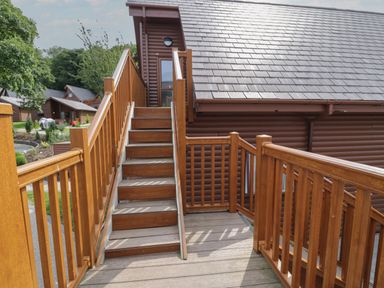 Wooden stairs and railings leading to a door on a log cabin exterior at Classic Lodge 15 in Dyserth