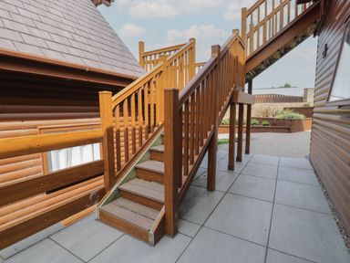 An outdoor wooden staircase next to a building with tiled floor at Classic Lodge 15 in Dyserth
