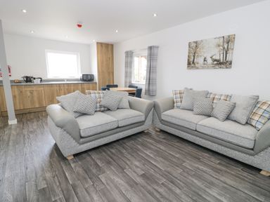 A living room with two sofas and a dining table next to a kitchen area at Luxury Lodge 46 in Dyserth