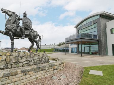 A statue of a warrior on a horse beside a modern building with a sign that says Marian Resort Spa in Dyserth