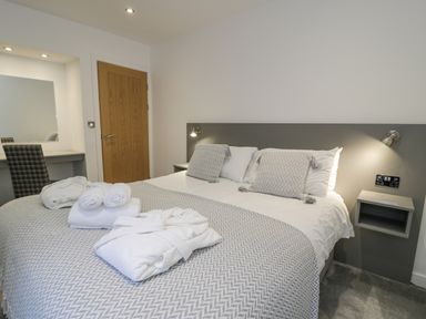 A bedroom with a bed with pillows and towels a chair and a wooden door at Luxury Lodge 46 in Dyserth