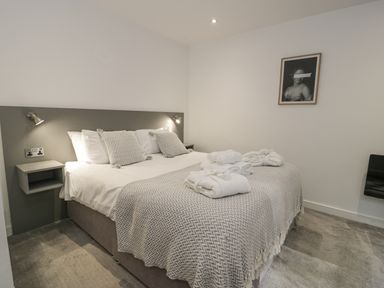 A bedroom with a double bed bedside shelves wall lamps and a framed picture at Luxury Lodge 46 in Dyserth