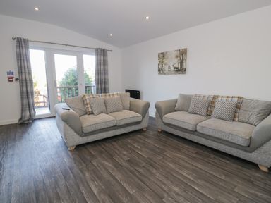 A living room with two sofas and a painting on the wall at Luxury Lodge 53 in Dyserth