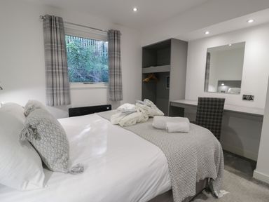 A bedroom with a bed a desk chair a mirror and an open wardrobe at Luxury Lodge 53 in Dyserth