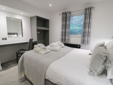 A bedroom with a bed towels on it a window with curtains a chair and a closet at Luxury Lodge 53 in Dyserth