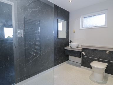 A bathroom with a toilet a sink with countertop a mirror and a window at Luxury Lodge 53 in Dyserth