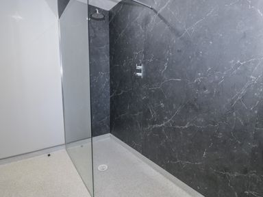 A walk in shower with a glass partition and black marble wall at Luxury Lodge 53 in Dyserth