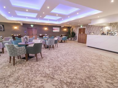 A lounge area with round tables and various upholstered chairs and a bar counter in Luxury Lodge 62 Dyserth