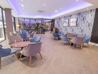 A lounge area with blue and beige chairs around wooden tables and wall decor at Luxury Lodge 62 in Dyserth