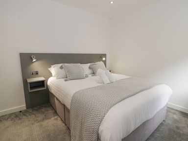 A bedroom with a double bed pillows bedside shelves and wall lights at Luxury Lodge 62 in Dyserth