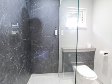 A bathroom with a walk-in shower and a toilet with a window above at Luxury Lodge 62 in Dyserth