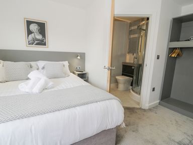 A bedroom with a bed, towels on the bed, an open door showing a bathroom, and an open wardrobe at Luxury Lodge 62 in Dyserth
