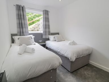 A bedroom with two single beds and a window with curtains at Luxury Lodge 62 in Dyserth