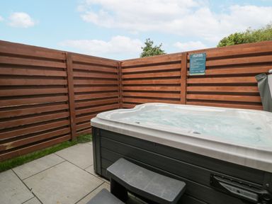 An outdoor area with a hot tub surrounded by wooden fencing at Luxury Lodge 62 in Dyserth