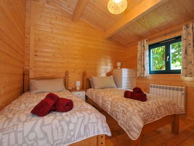 A bedroom with two beds and a chest of drawers at Owl Lodge in Menheniot