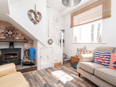 A living room with a fireplace under stairs and sofas with nautical cushions at The Old Coastguard Tower Buncrana County Donegal
