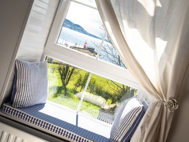 A window seat with blue and white striped cushions and pillows overlooking a garden and water at The Old Coastguard Tower Buncrana County Donegal