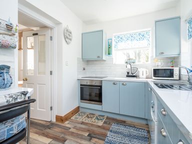 A kitchen with blue cabinets a stainless steel oven a microwave a kettle and a sink at The Old Coastguard Tower Buncrana in Buncrana County Donegal