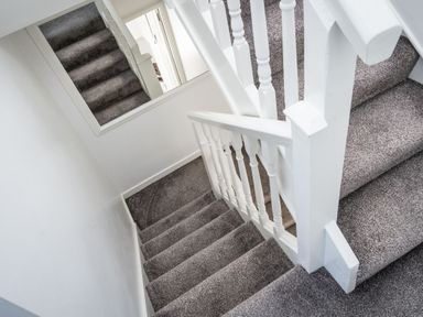 A carpeted staircase with white railings and a large mirror on the wall at The Old Coastguard Tower Buncrana in Buncrana County Donegal