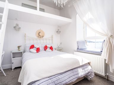 A bedroom with a bed and two red and white life ring pillows by a window seat at The Old Coastguard Tower Buncrana in Buncrana County Donegal