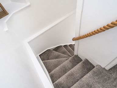 A staircase with grey carpet and a rope handrail on a white wall at The Old Coastguard Tower Buncrana in Buncrana County Donegal