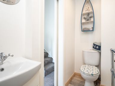 A small bathroom with a toilet and sink next to a doorway showing carpeted stairs at The Old Coastguard Tower Buncrana in Buncrana County Donegal