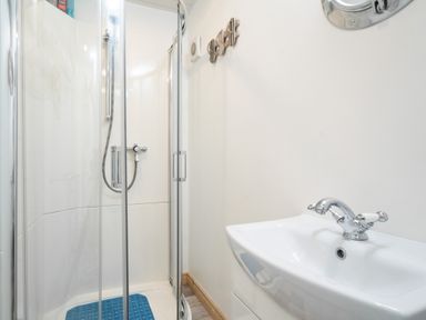 A bathroom with a corner shower enclosure and a white sink with a chrome faucet at The Old Coastguard Tower Buncrana in Buncrana County Donegal