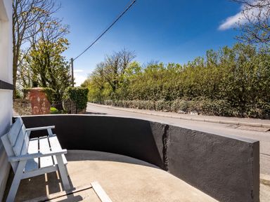 A bench on a curved patio next to a road with trees and bushes at The Old Coastguard Tower Buncrana County Donegal