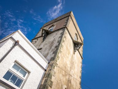 An upward view of a tower attached to a white building against a blue sky at The Old Coastguard Tower Buncrana in Buncrana County Donegal
