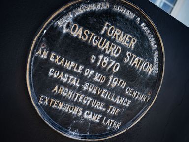 A round historical plaque about a former coastguard station from 1870 on a dark wall at The Old Coastguard Tower Buncrana County Donegal